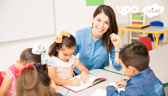 Smiling teacher and children at a desk in a classroom
