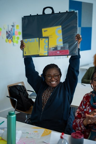 Woman holding up a pack of YPO resources