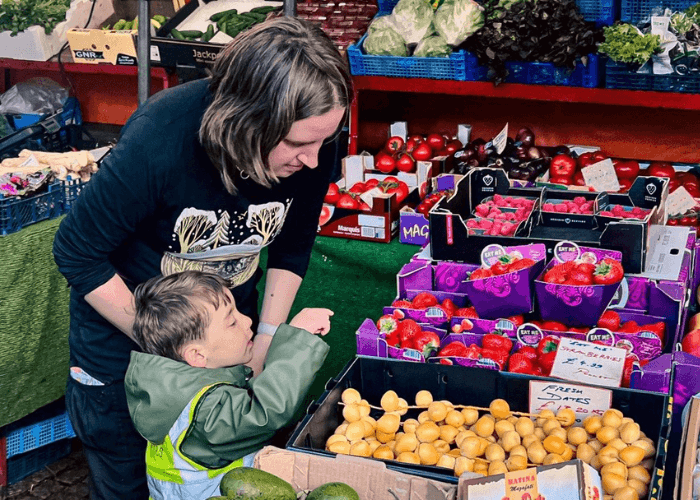 adult and child interacting with a fruit and vegetable table